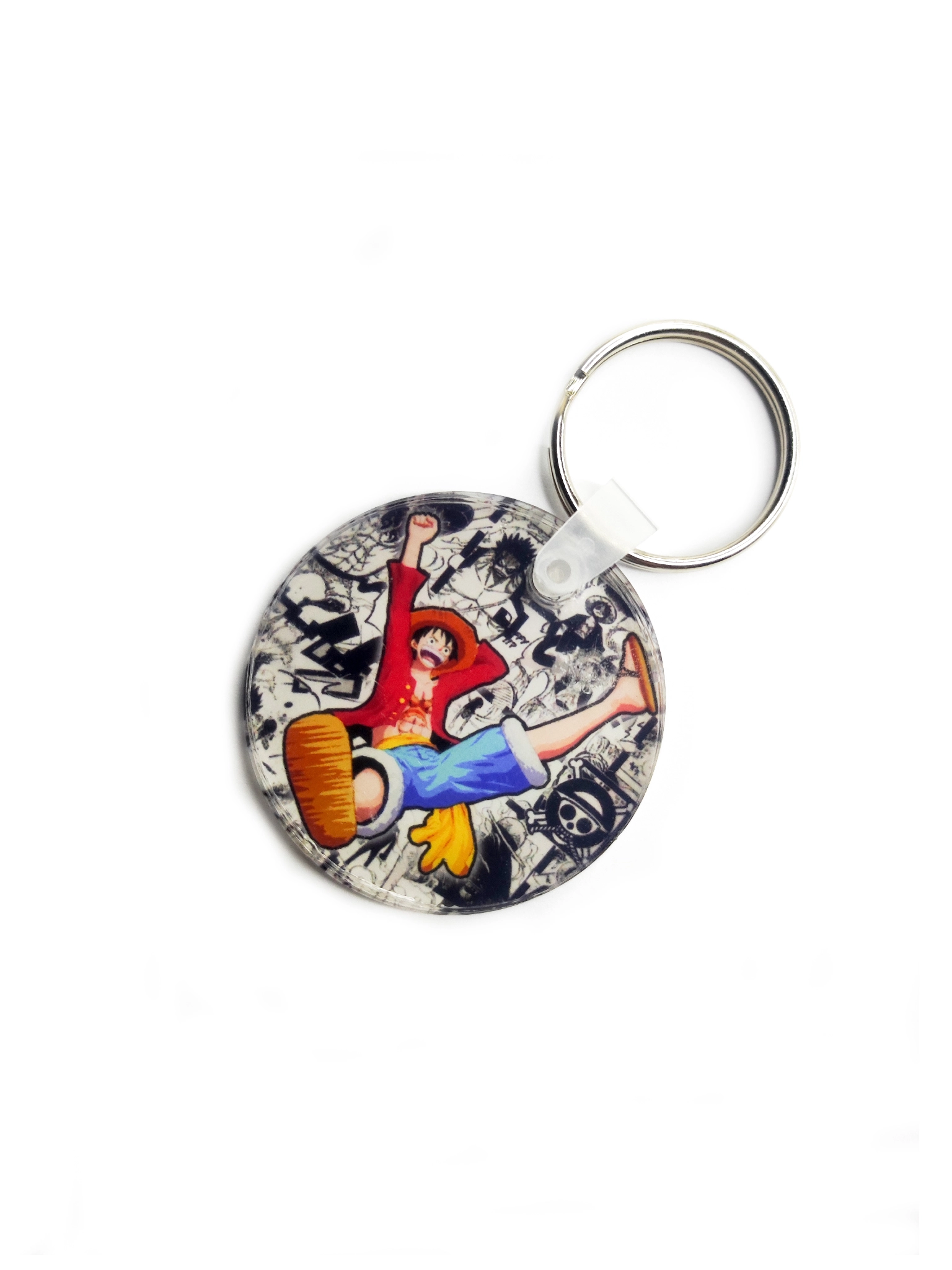 Llavero circular transparente con un diseño de Luffy de One Piece saltando y elementos de manga de fondo.