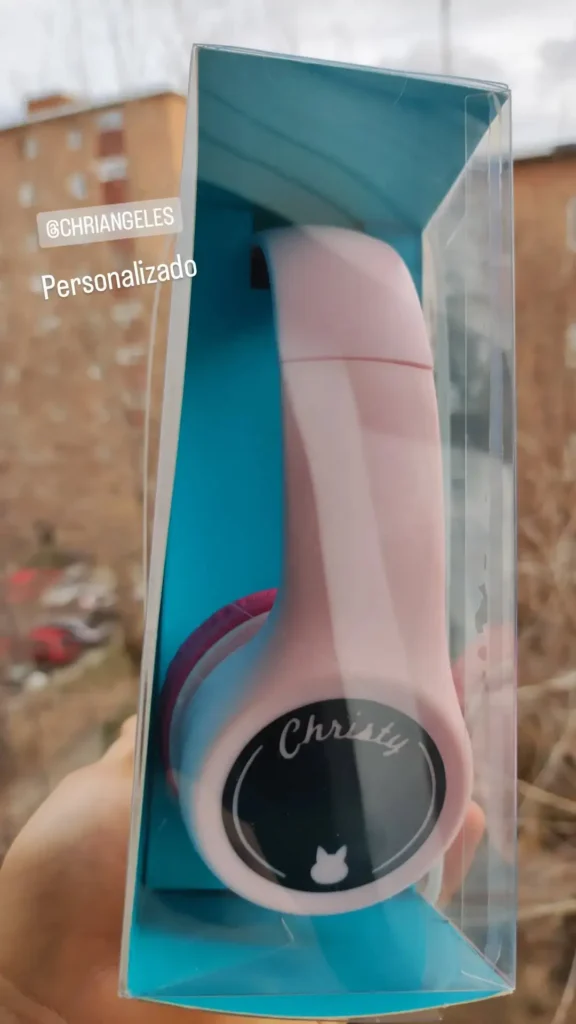 Auriculares de diadema inalámbricos de color rosa en caja, personalizados con el nombre "Christy" y un pequeño icono de gato.